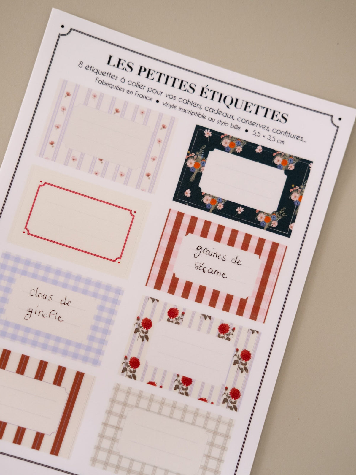 Détail des étiquettes adhésives pour bocaux, avec les mentions manuscrites « graines de sésame » et « clous de girofle ».