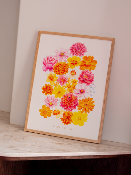 Affiche florale « La Belle Saison » aux fleurs roses, jaunes et orange, dans un cadre en bois sur du marbre clair.