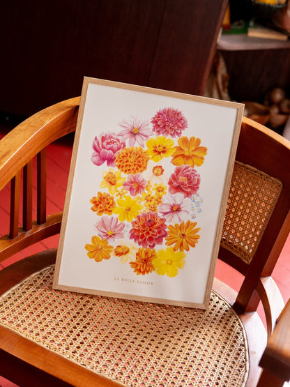 ffiche de fleurs colorées « La Belle Saison », présentée dans un cadre en bois clair sur une chaise cannée.