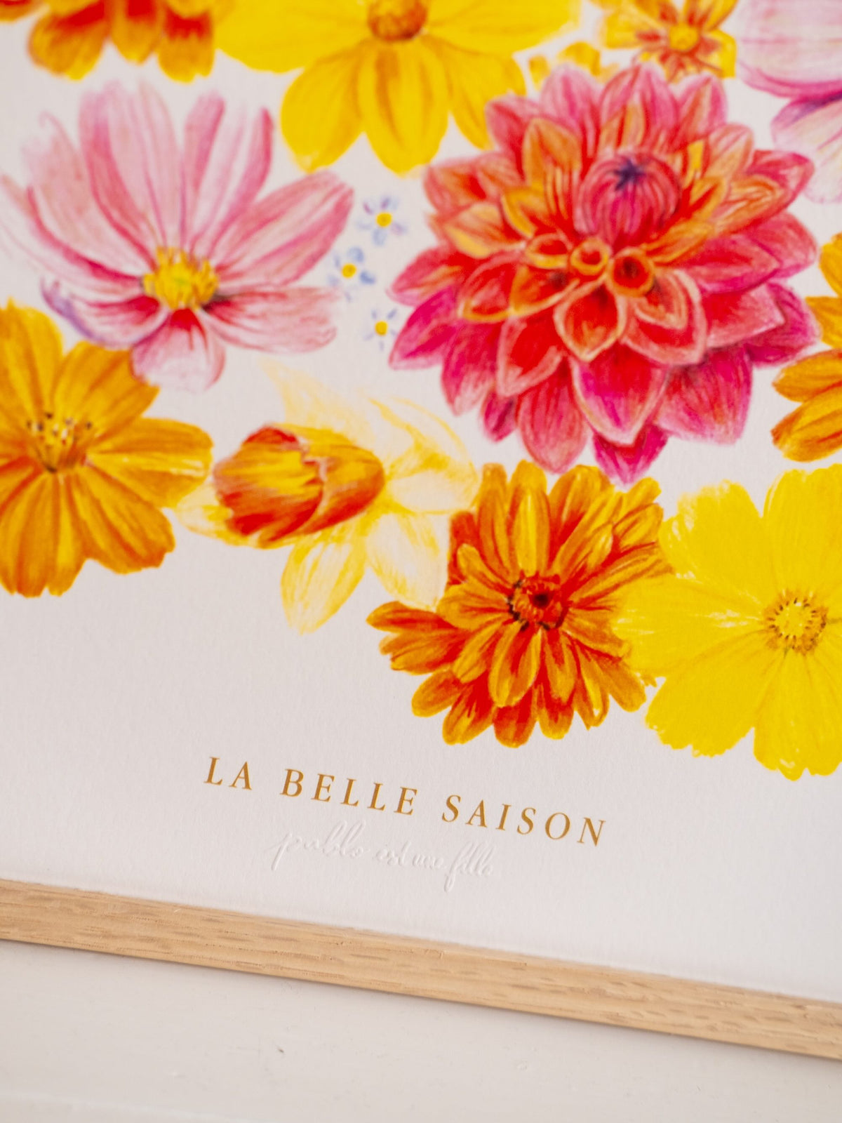 Détail de l’affiche « La Belle Saison » : fleurs roses, jaunes et orange illustrées au-dessus de l’inscription.
