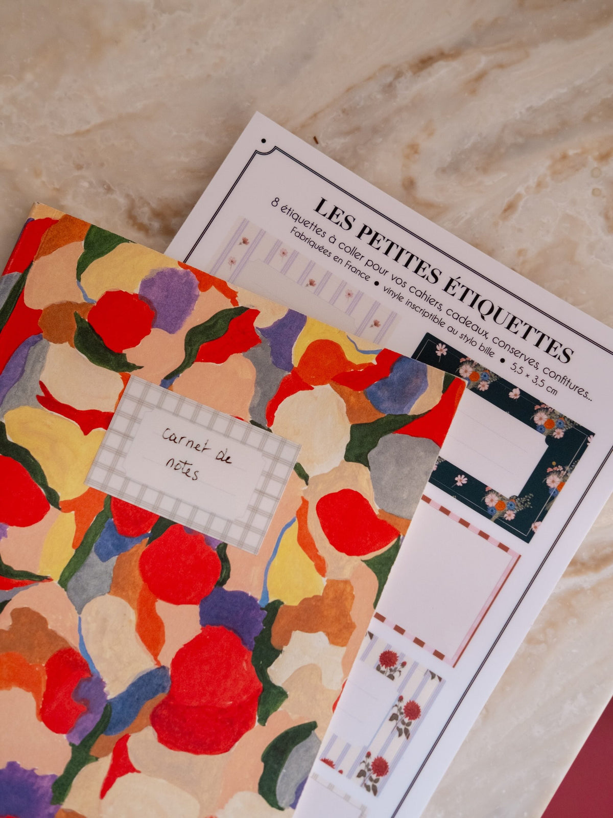 Étiquette autocollante à carreaux marquée « carnet de notes », collée sur un carnet coloré, avec la planche derrière.