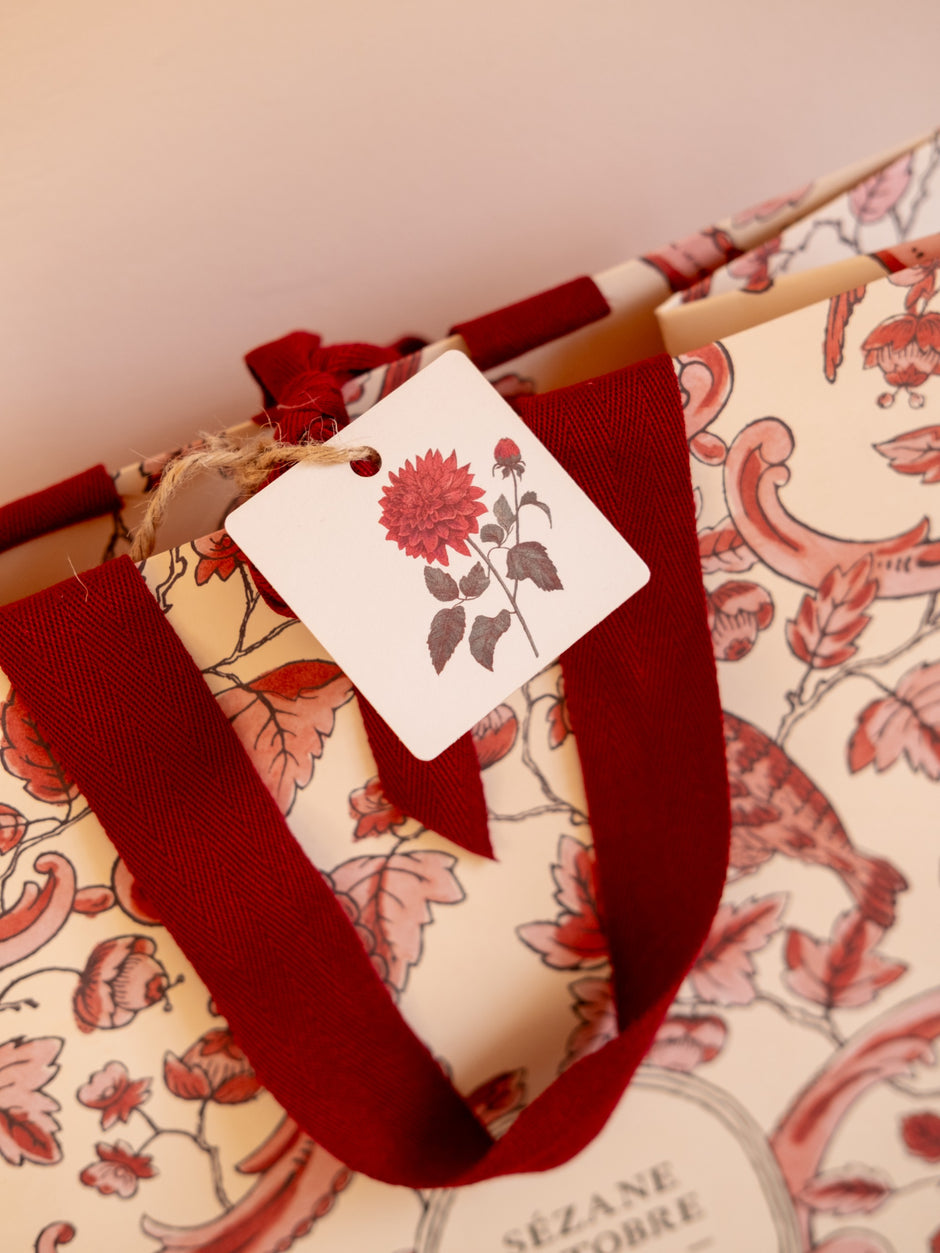 Étiquette cadeau dahlia rouge illustrée – en situation sur sac fleuri | Pablo est une fille